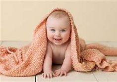 a smiling baby wrapped in a blanket on the floor