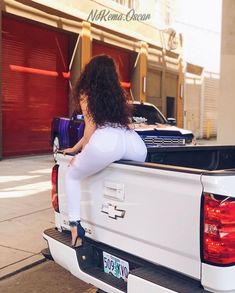 a woman sitting in the back of a white truck