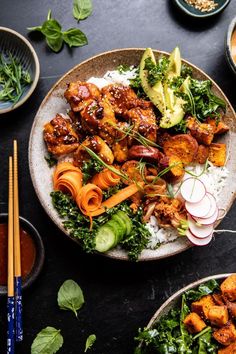 a plate with meat, vegetables and rice next to chopsticks on a table