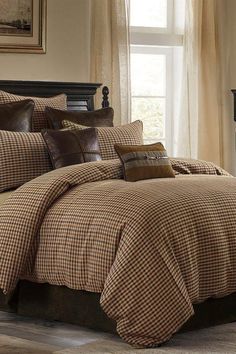 a bed in a bedroom with brown and tan plaid comforter