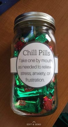 a jar filled with lots of candy sitting on top of a wooden table next to a sign