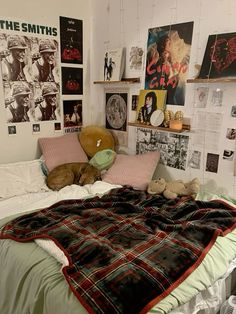 a bed with two teddy bears on top of it in a room filled with posters