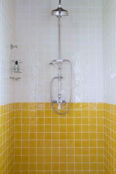 a yellow and white tiled bathroom with shower head