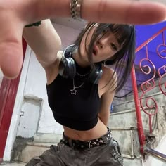 a woman with headphones is pointing her finger at the camera while standing in front of stairs