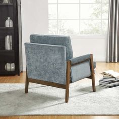 a blue chair sitting on top of a wooden floor next to a bookshelf