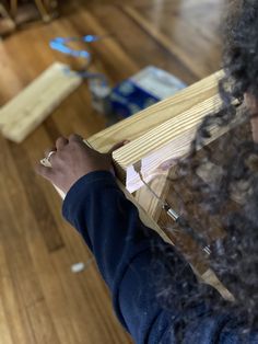 a person holding a piece of wood on top of a hard wood floor