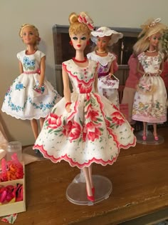 three dolls in dresses and hats on a table