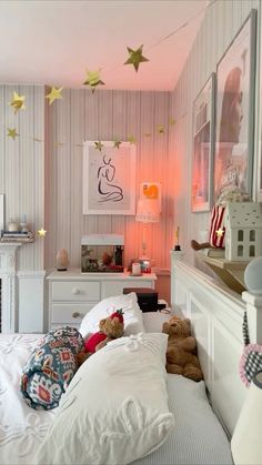 there is a teddy bear on the bed in this room with pink walls and stars hanging from the ceiling