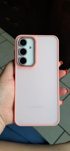 a woman's hand holding an iphone case with three buttons on it, in front of a tiled floor