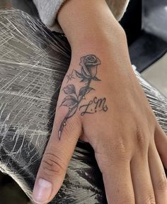 a woman's hand with a rose tattoo on her left thumb and the word love written in cursive font