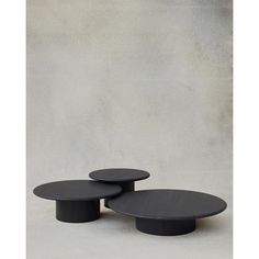 three black tables sitting next to each other in front of a gray wall and floor