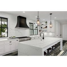 a large kitchen with white cabinets and marble counter tops