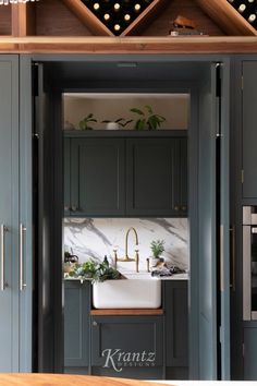 a kitchen with gray cabinets and marble counter tops, gold faucets and brass accents