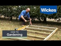 a man kneeling down to build a garden bed