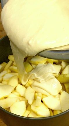 a pot filled with potatoes and cream being poured into it