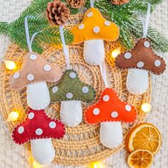 several felt mushrooms are sitting on a wicker tray with pine cones and orange slices