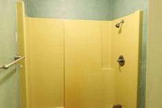 a yellow shower stall in a bathroom with blue walls