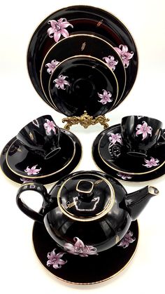 a black tea set with pink flowers on it