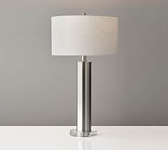 a lamp that is sitting on top of a white table next to a gray wall