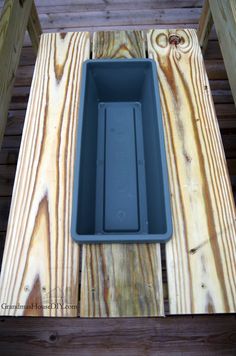 an empty plastic container sitting on top of a wooden table next to a bench with wood planks