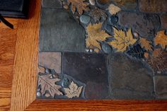 a wooden table topped with lots of leaves on top of stone flooring next to a phone