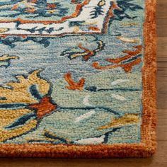 a blue and orange area rug on a wooden floor with a wood table in the background