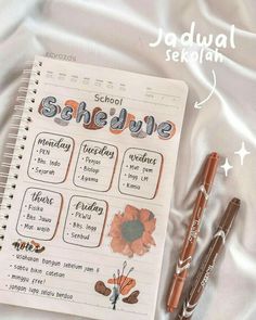 an open notebook with school schedule and two pens next to it on a bed sheet