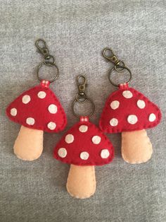 two red mushrooms with white dots on them sitting on a gray surface, one is being held by a pair of metal hooks