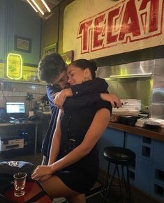 a man and woman hugging in a restaurant kitchen next to a table with food on it