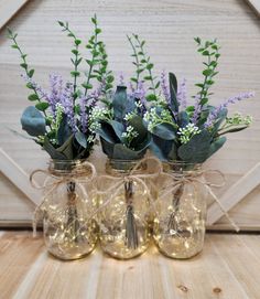 three glass vases filled with flowers and greenery