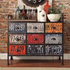 a clock mounted to the side of a brick wall next to a shelf with license plates on it