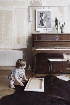 a young child playing with a piano in front of an empty box on the floor