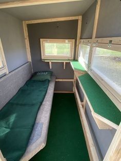 the inside of a tiny house with green carpeting and windows on each side of the room