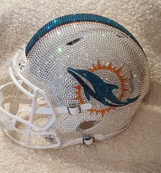 a miami dolphins football helmet is shown on a white carpet with blue and orange accents