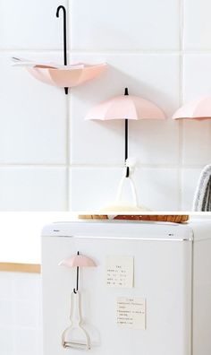 a white refrigerator freezer sitting inside of a kitchen next to two pink umbrellas