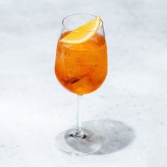 an orange slice is placed on the rim of a wine glass filled with ice and water