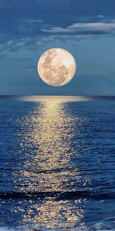 the full moon shines brightly in the sky above the ocean water as it reflects on the surface of the water