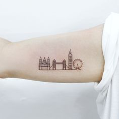 a woman's arm with a small city skyline tattoo on the left inner arm