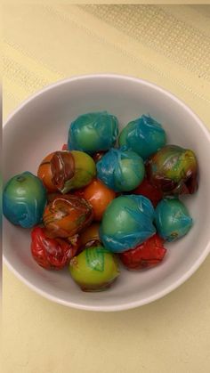 a white bowl filled with lots of different colored fruit on top of a yellow table