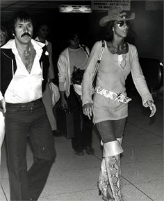 the man and woman are walking through the airport together, wearing cowboy hats on their heads