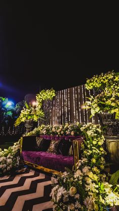 a purple couch sitting on top of a black and white checkered floor covered in flowers