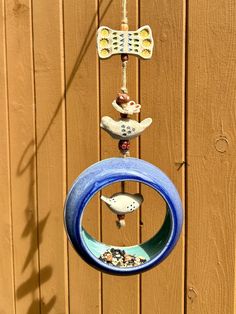 a wind chime hanging from the side of a wooden fence with birds on it