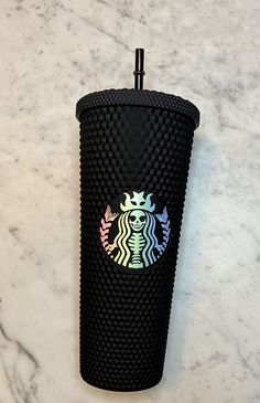 a black starbucks cup sitting on top of a marble counter