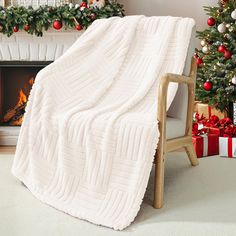 a white blanket is draped over a chair in front of a christmas tree and fireplace