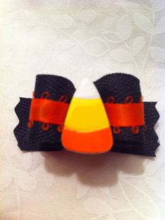 an orange and black candy corn corsage on a white tablecloth with red ribbon