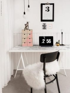 a white desk topped with a laptop computer next to a black and white wall mounted clock