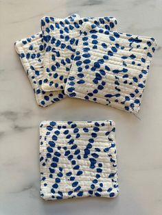 four blue and white patterned napkins on a marble counter top, with one folded in half