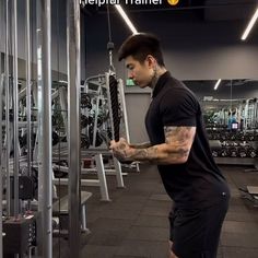 a man with tattoos standing in front of a gym machine