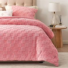 a bed with a pink comforter and pillows