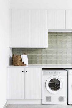 a washer and dryer in a white laundry room with green tile backsplash